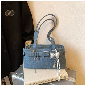 Detail of denim shoulder bag with metal belt buckle and silver butterfly charm