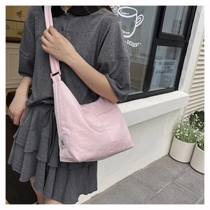Detailed outdoor shot of a pink nylon crescent crossbody bag with adjustable strap