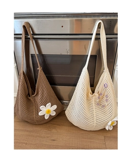 Detail von handgestrickten Tragetaschen mit Gänseblümchen-Applikationen in Braun und Beige