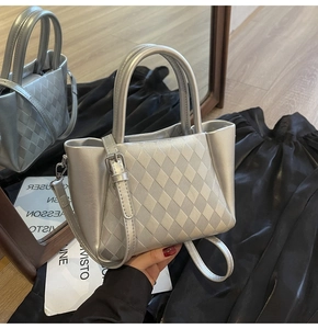 Detail of silver metallic handbag with diamond lattice embossing and shoulder strap