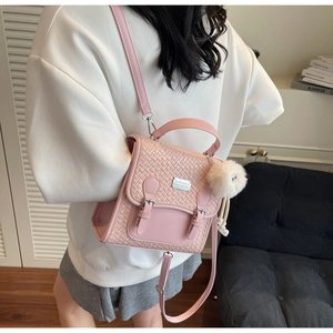 Détail d'un sac à dos rose clair à texture tissée avec boucles argentées et pompon