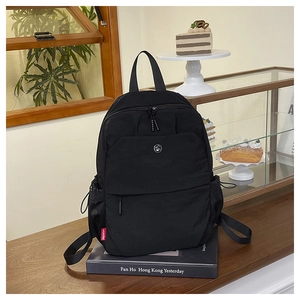 Detail of black nylon backpack with a zipper pocket and a side mesh bottle holder