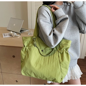 Detail of light green nylon tote bag with drawstring and front snap pocket