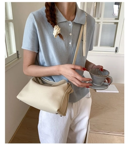 Detail of beige lychee grain leather handbag with adjustable strap and metal bottom studs