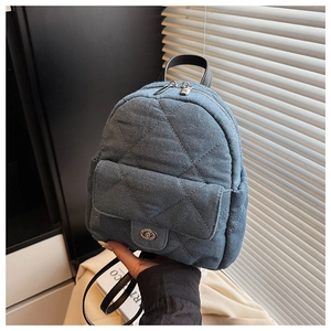 Detail of blue quilted denim backpack with silver twist lock and black leather handle