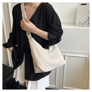 Detail of a cream nylon hobo bag with pleated texture and silver floral metal logo buckle