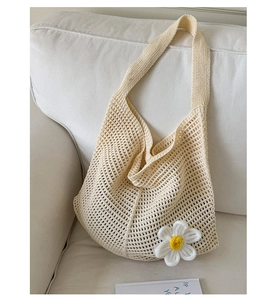 Detailaufnahme der gewebten Netzstruktur und der handgefertigten Gänseblümchen am Strickbeutel