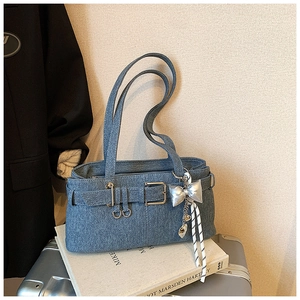 Blue denim bucket bag detail featuring metal buckles and silver butterfly pendant on luggage