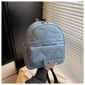 Detail of light blue quilted denim backpack with diamond stitching and metal turn-lock