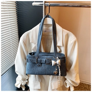 Detail of fabric shoulder bag with metallic bow charm and silver buckle strap