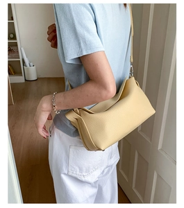 Detail of the side fold structure and silver hardware on a yellow leather crossbody bag