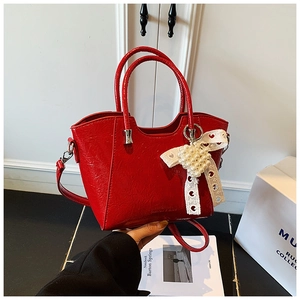 Detail of red patent leather bucket bag with white lace bow and pearl heart charm