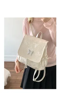 Vue détaillée du sac à dos jacquard crème avec motifs papillons et boucle métallique