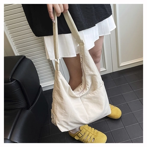 Detail view of cream nylon tote bag featuring adjustable strap and spacious hobo design