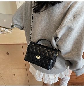 Detail shot of the black quilted shoulder bag with chain strap and metallic clasp closure