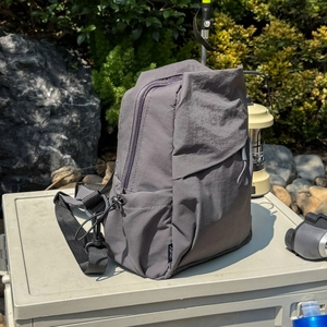 Detail of dark gray waterproof nylon backpack with adjustable straps in outdoor camping setting