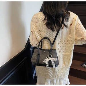 Detail der schwarzen Pailletten-Beuteltasche mit weißer Spitzenschleife am Outfit