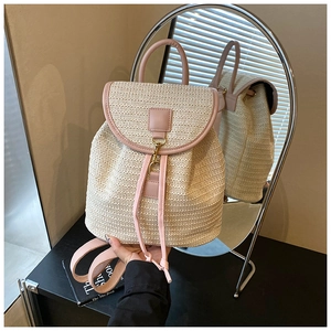 Detail view of woven straw backpack with pink leather straps reflected in a mirror