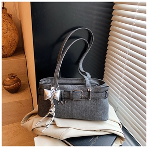 Close-up of gray denim bucket bag with silver butterfly charms on a beige blazer