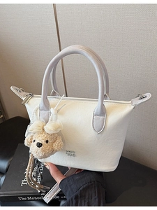 Sac seau minimaliste en cuir beige avec charme d'ours en peluche et anses contrastées