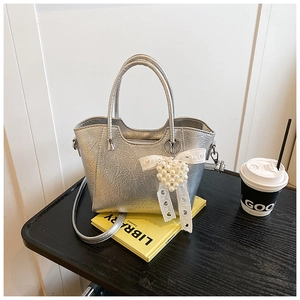 Detail of silver metallic bucket bag with pearl heart pendant and lace bow accent