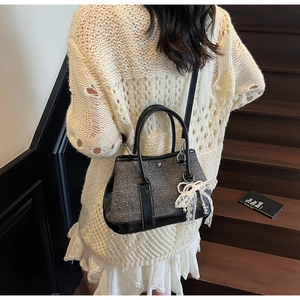 Detail der Tweed-Eimertasche mit schwarzem Lederbesatz und weißer Spitzenschleife mit Perle