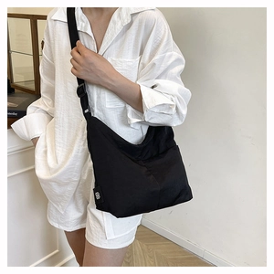 Close-up of minimalist black nylon crescent bag with adjustable strap on a model