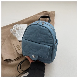 Detailed view of blue denim quilted mini backpack with front metal twist lock pocket