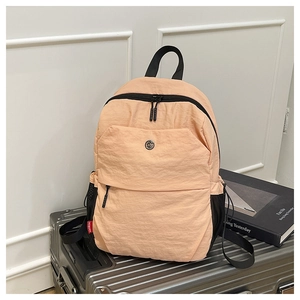 Detail of apricot nylon backpack showing fabric texture and a red MOBORN side label