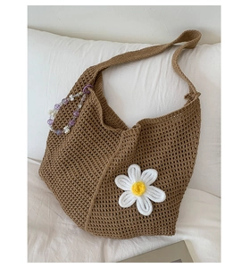 Detailansicht der handgestrickten Tasche mit weißer Gänseblümchenblume und Perlenanhänger