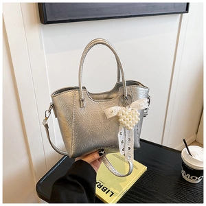 Detailed shot of silver metallic bucket bag with pearl heart charm and lace bow decor