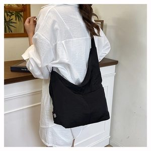 Detailed back view of a minimalist black nylon tote bag on a model in a cozy interior