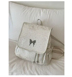 Détail de l'ornement papillon en métal et texture florale sur sac à dos beige