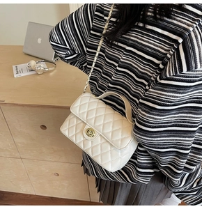 Close-up of a white quilted small square bag with a gold chain strap and metal lock