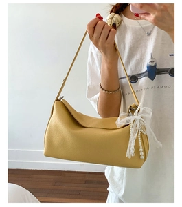 Close-up of mustard yellow faux leather bag with lace bow and pearl charm detail