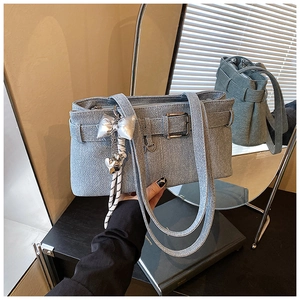 Detail of light blue denim bucket bag with silver butterfly charm and metal buckle