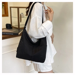 Close-up of lightweight black nylon tote bag showing minimal design and wide shoulder strap