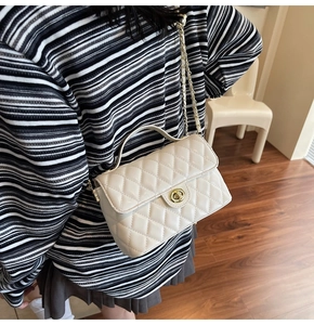 Detail showing cream quilted mini square bag with gold twist lock and chain strap