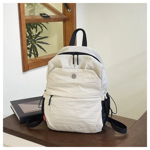 Detailed close-up of beige nylon backpack texture with red MODERN tag on a wooden table