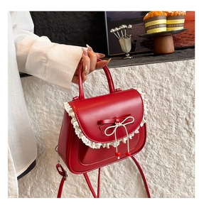 Dettaglio della borsa in pelle rossa con pizzo bianco e raffinati fiocchi decorativi