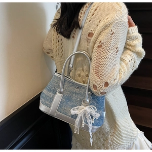 Detail der blauen Denim-Beuteltasche mit silbernem Lederbesatz, Schleife und Perle