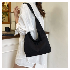 Close-up of black nylon tote bag on shoulder showing large capacity and sleek fabric