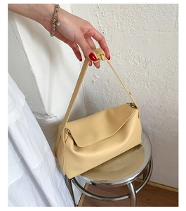 Detail of light yellow lychee grain leather handbag with knotted strap and metal ring