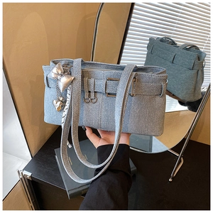 Detail of light blue denim bucket bag with silver butterfly and heart charm accents