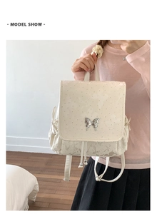 Détail d'un sac à dos blanc avec broderie papillon et boucle en strass argentés