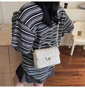 Detailed side view of a cream quilted leather crossbody bag with golden chain strap