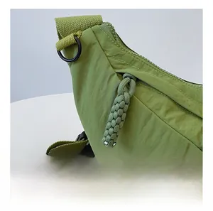 Dettaglio della cerniera fluida con tiralampo in tessuto e anello a D in nylon su borsa verde