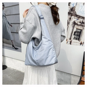 Detailed side view of a spacious light blue nylon tote bag worn by a model