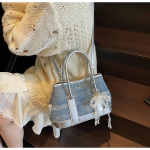 Denim-Beuteltasche mit Silberbesatz und Perlen-Schleifen-Anhänger an einem Modell