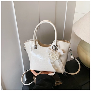 Detail of cream bucket bag with pearl heart charm and elegant polished finish